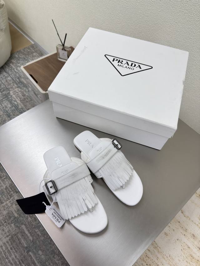 Prada vintage tasseled flip-flops. A simple white flat-soled design with a trian
